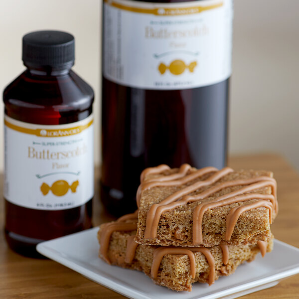 A bottle of LorAnn Oils Butterscotch Super Strength Flavor on a counter next to a plate of brown food.