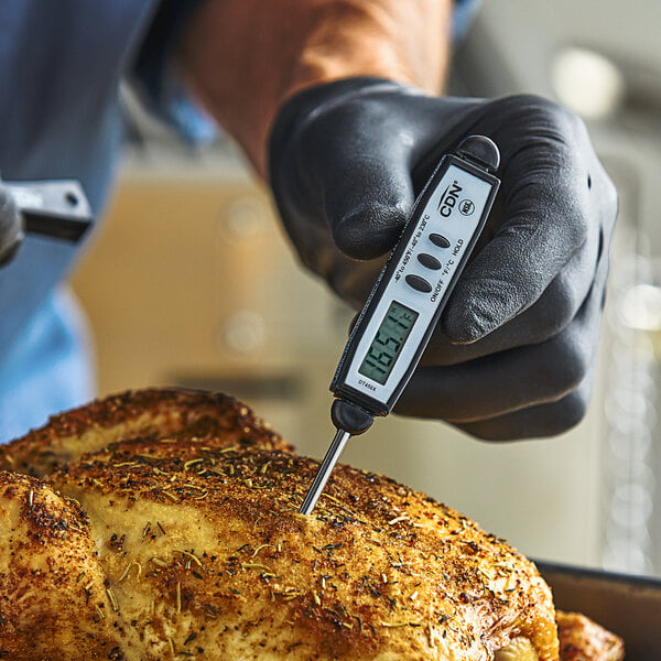 A person in gloves using a CDN DT450X digital pocket probe thermometer to measure the temperature of a roast.