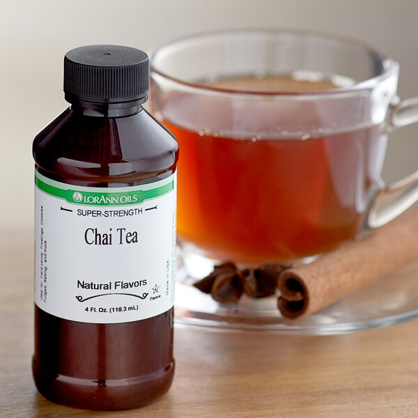 A bottle of LorAnn Oils Chai Tea flavoring next to a glass of chai tea.