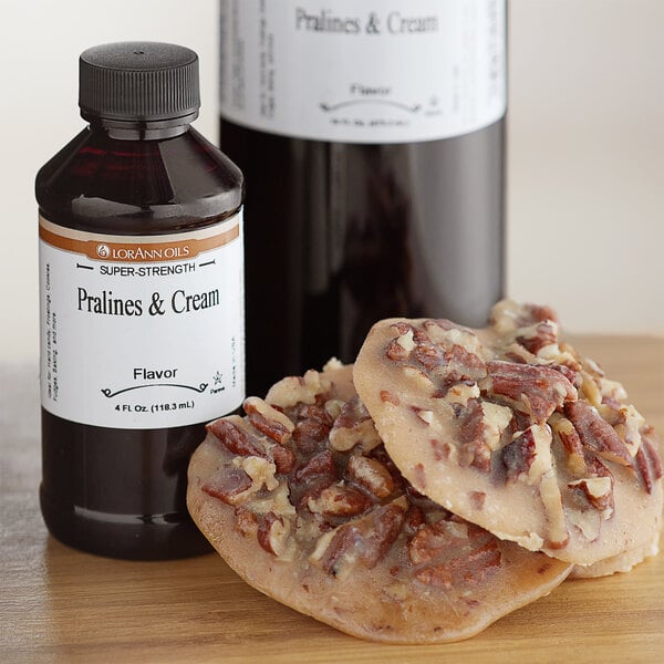 A bottle of LorAnn Oils Pralines & Cream flavoring on a counter next to a pile of pecan candies.