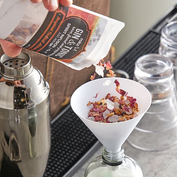 A person pouring a mixture into a glass funnel.