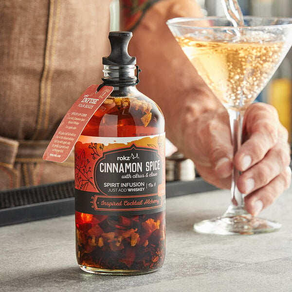 A man pouring Rokz Cinnamon Spice into a glass of liquid.