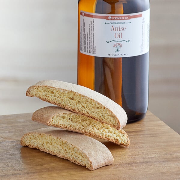 A stack of cookies on a table next to a bottle of LorAnn Oils Anise Super Strength Flavor.