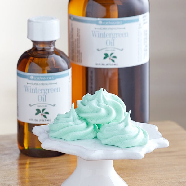 A bottle of LorAnn Oils All-Natural Wintergreen Super Strength Flavor on a counter among other bottles of essential oils.