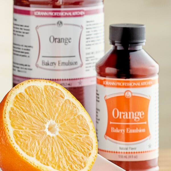 A bottle of LorAnn Oils All-Natural Orange Bakery Emulsion next to half an orange.