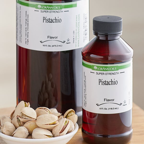 A bottle of LorAnn Pistachio Super Strength Flavor on a counter next to a bowl of pistachios.