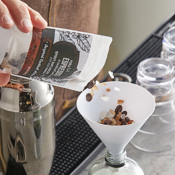 A hand pouring coffee beans into a glass jar.