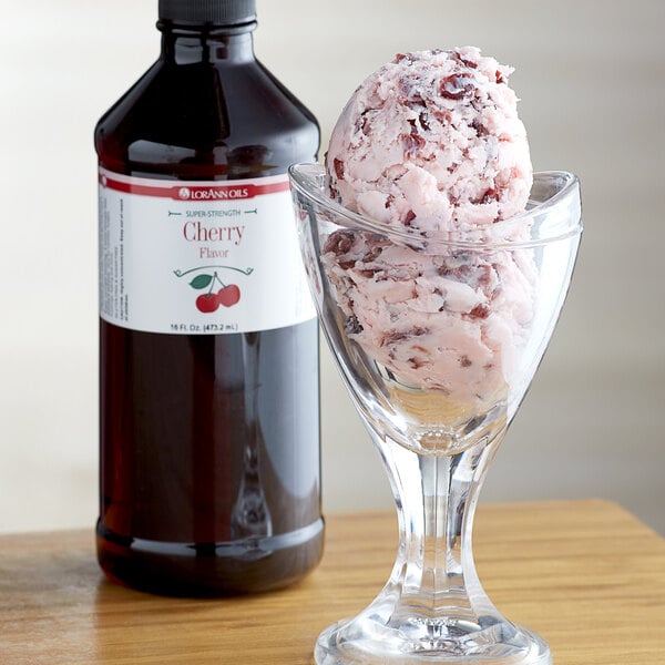 A glass of ice cream with cherry syrup next to a bottle of LorAnn Cherry Super Strength Flavor.