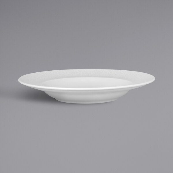 A close-up of a RAK Porcelain white deep plate with an embossed rim.