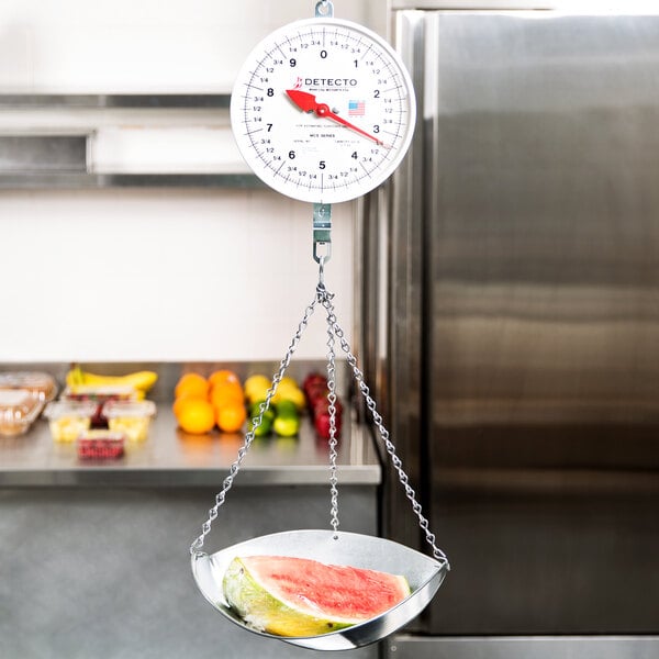 A Cardinal Detecto hanging scale with a watermelon on it.