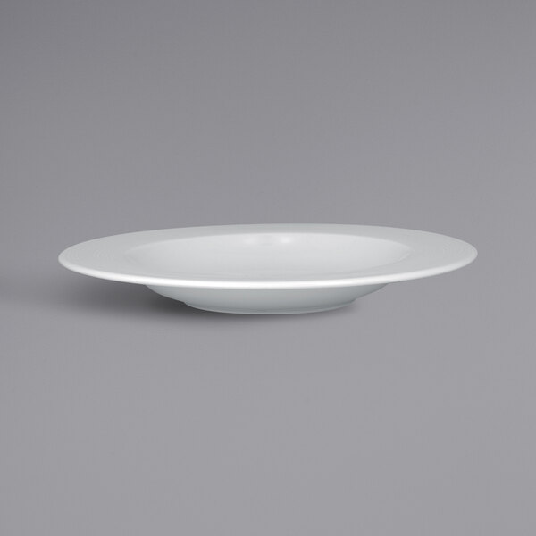 A close up of a RAK Porcelain white embossed wide rim deep porcelain plate.