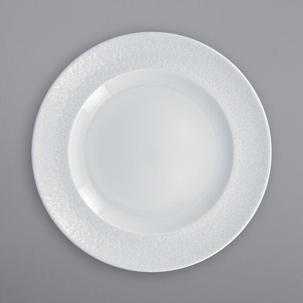 A close up of a RAK Porcelain wide rim porcelain plate with a textured surface and white rim.