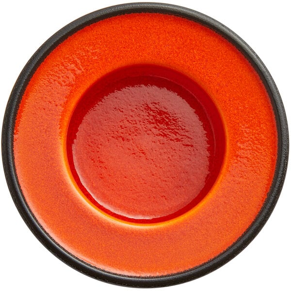 An orange porcelain saucer with a black rim.