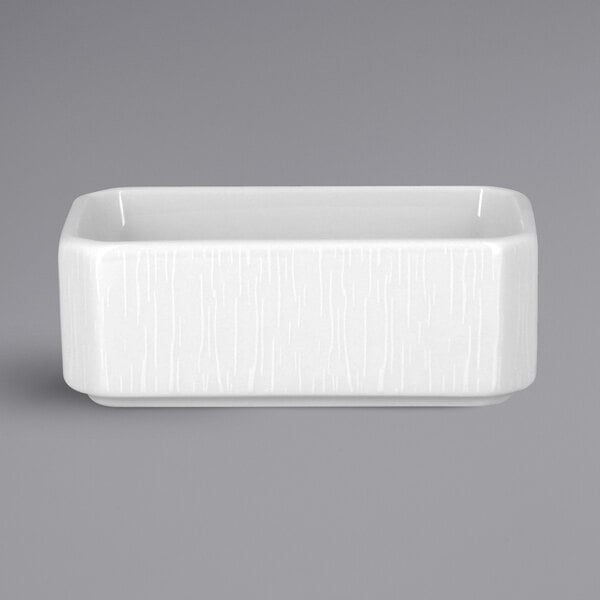 A white rectangular RAK Porcelain sugar caddy with an embossed design and a handle.