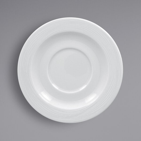 A close-up of a RAK Porcelain bright white saucer with a circular pattern.