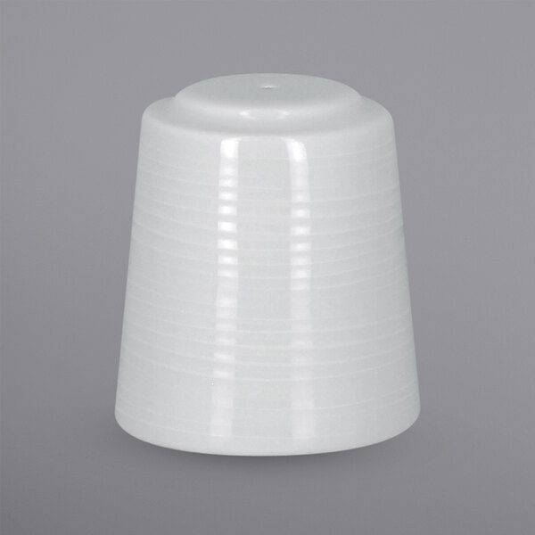 A white porcelain pepper shaker with an embossed design on a gray surface.