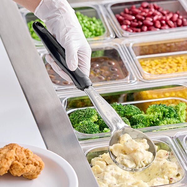 A person in gloves using a Vollrath Jacob's Pride black round portion spoon to serve food.