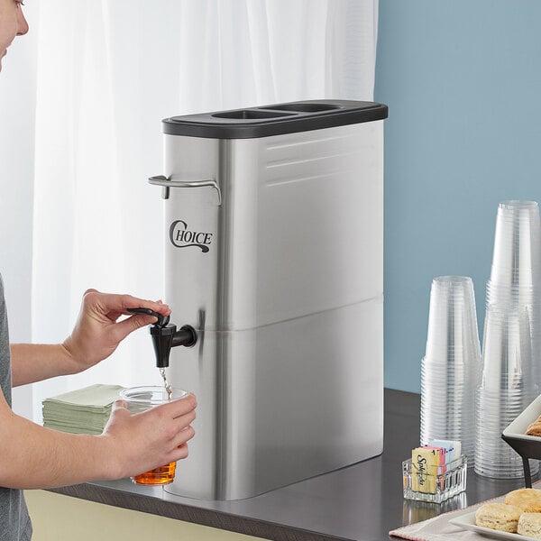 A man pouring iced tea from a Choice 5 Gallon Slim Iced Tea Dispenser into a glass.