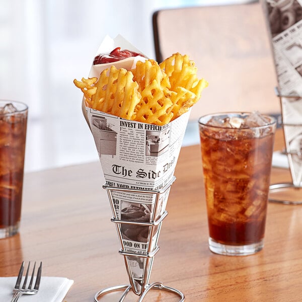 A newspaper cone filled with french fries on a table with a glass of iced tea.