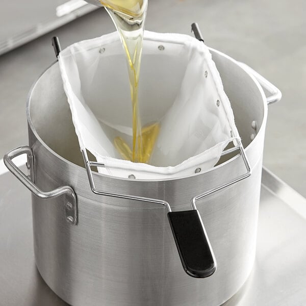 A person pouring a bag of oil into a metal pot.