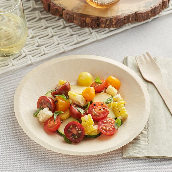 A TreeVive by EcoChoice wooden round plate with salad and vegetables on a table.