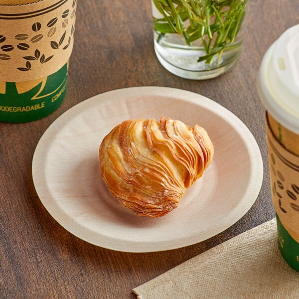 A TreeVive by EcoChoice compostable wooden plate with a pastry and a cup of coffee on a table.