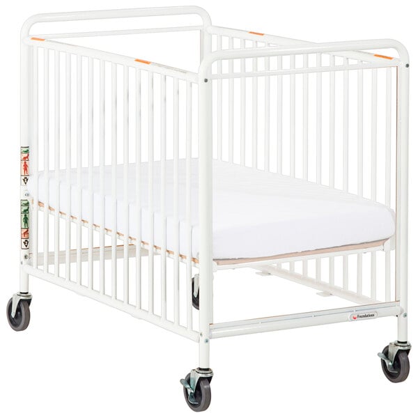 A white Foundations crib with clearview end panel and wheels.