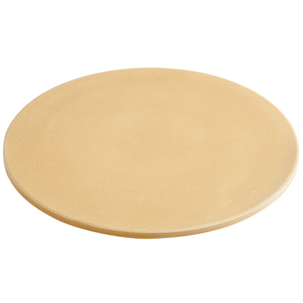 An Outset round cordierite pizza stone on a table.