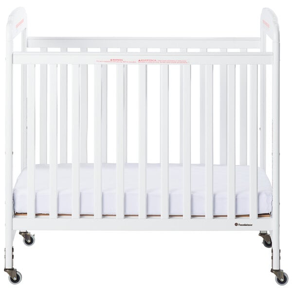 A white Foundations Serenity wood crib with a mattress on it.