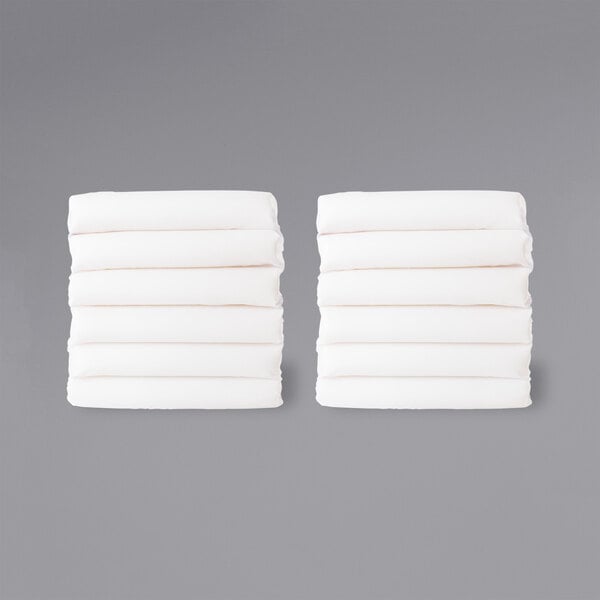 A stack of white folded Foundations CozyFit cot sheets.
