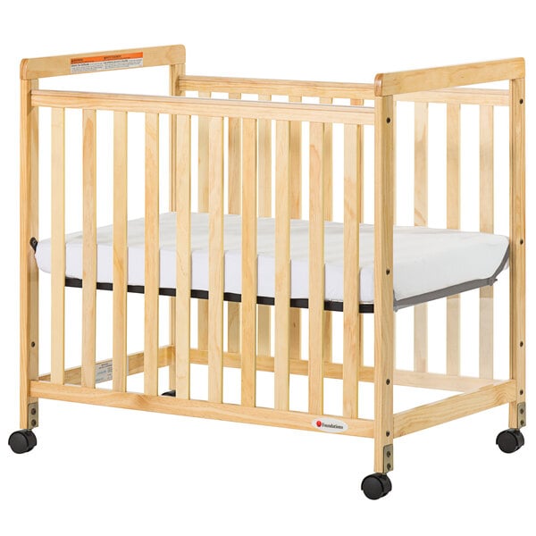 A natural wood Foundations SafetyCraft crib with clearview sides and wheels.