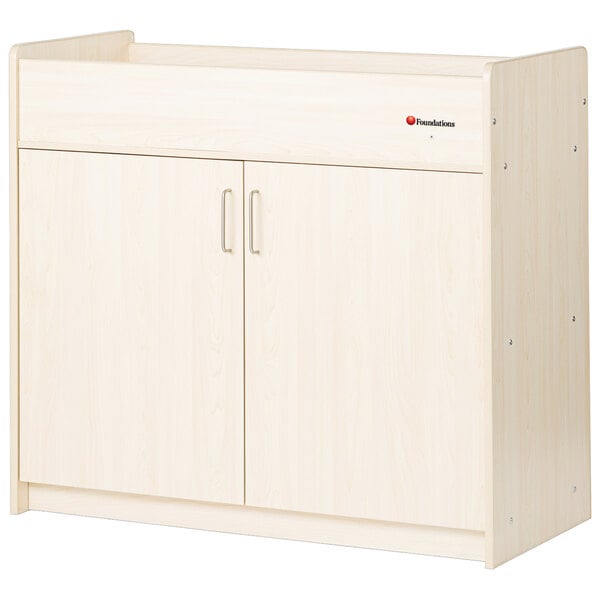 A natural maple wood baby changing cabinet with doors.