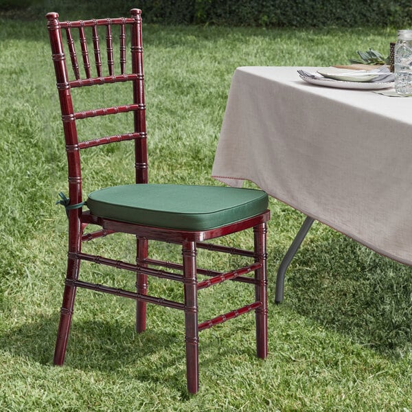 A Lancaster Table & Seating mahogany Chiavari chair with a green cushion on a table.