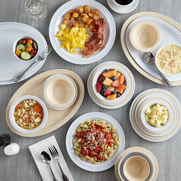 A set of bone white smooth melamine ramekins displayed among various plates and bowls of food.