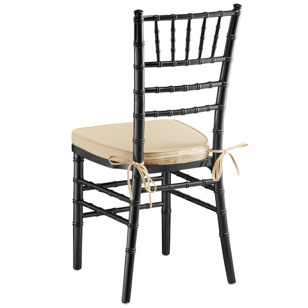A black Lancaster Table & Seating Chiavari chair with a tan cushion.