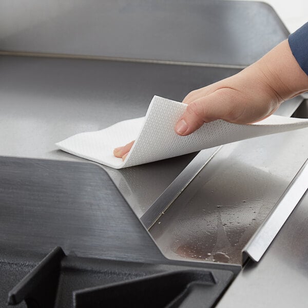 a hand holding a paper towel over a stove