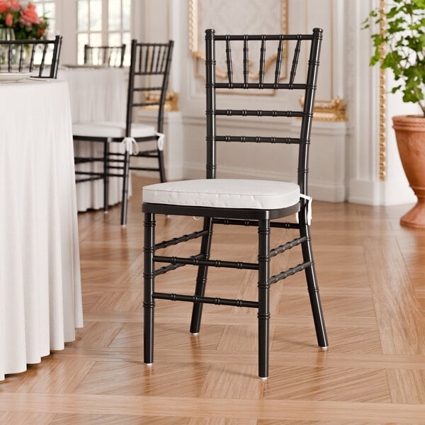 A black wood Chiavari chair with a white cushion.