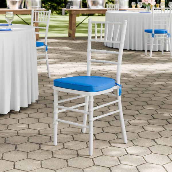 A white wood Chiavari chair with a blue cushion.