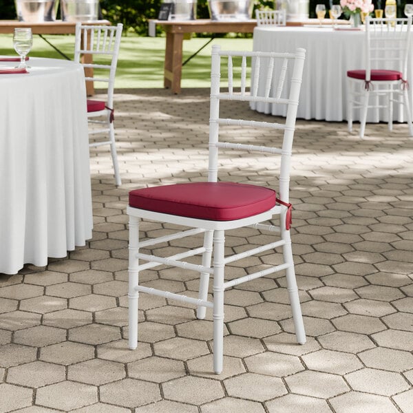 A white wood Chiavari chair with a wine red cushion.
