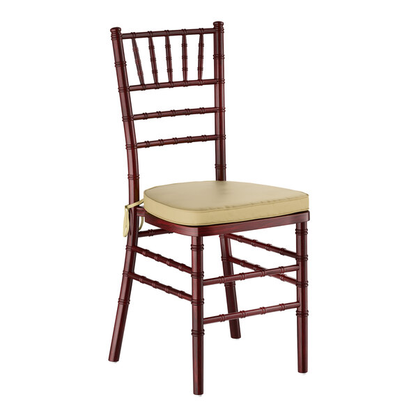 A mahogany wood Chiavari chair with a gold cushion.
