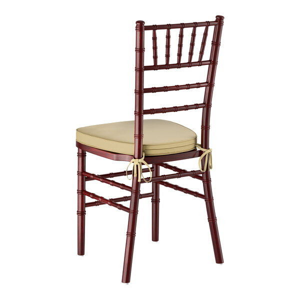 A mahogany wood Chiavari chair with a gold cushion tied to the seat.