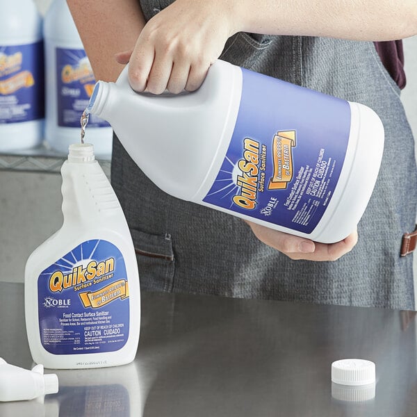 A person pouring Noble Chemical QuikSan liquid into a jug.