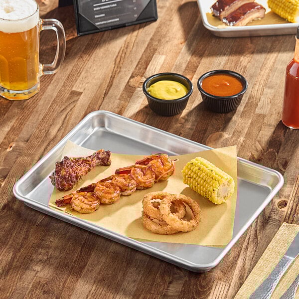 A heavy-duty quarter size aluminum sheet pan with a wire-in rim, shown holding a meal including shrimp skewers, a chicken drumstick, onion rings, and corn on the cob.