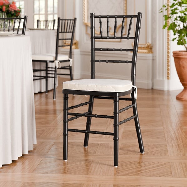 A black wood Chiavari chair with an ivory cushion.