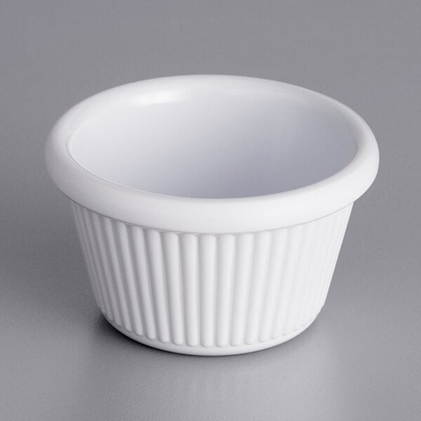 An Acopa white fluted melamine ramekin on a gray surface.