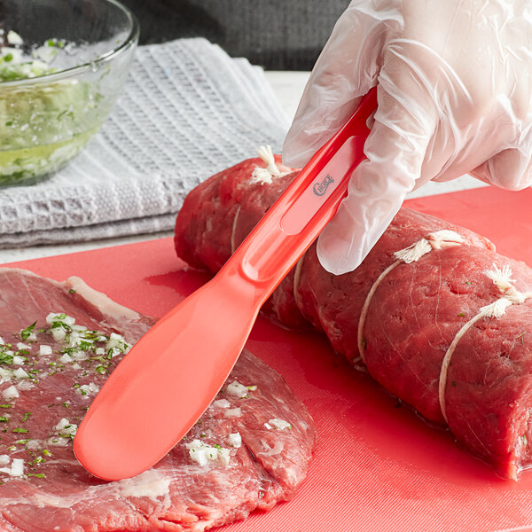 A person using a Choice sandwich spreader to cut meat on a cutting board.