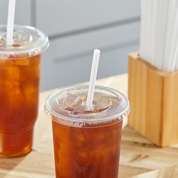 A plastic cup of iced tea with a white wrapped straw in it.