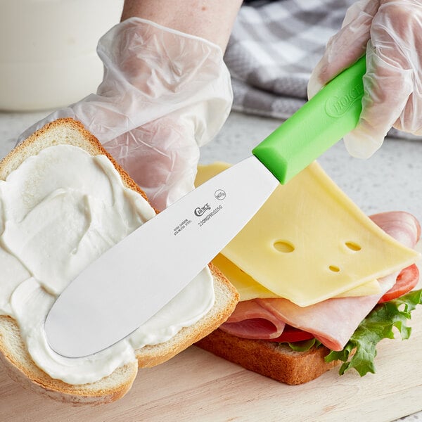 a person holding a knife over a sandwich