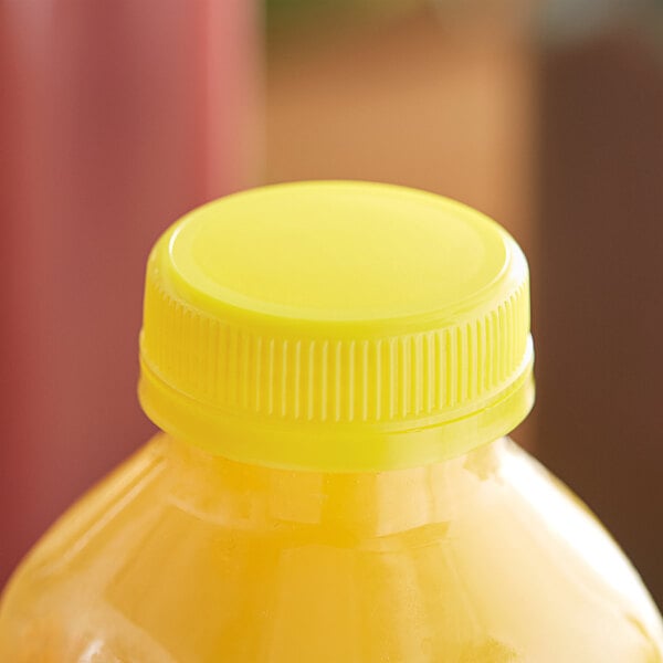 A close-up of a yellow plastic bottle cap on a yellow juice bottle.