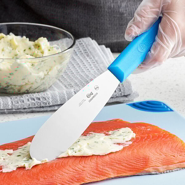 a knife spreading butter on a piece of fish
